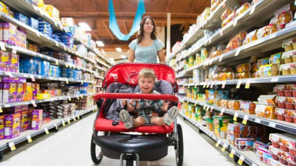 A woman shops in a grocery store while pushing a stroller with a child
