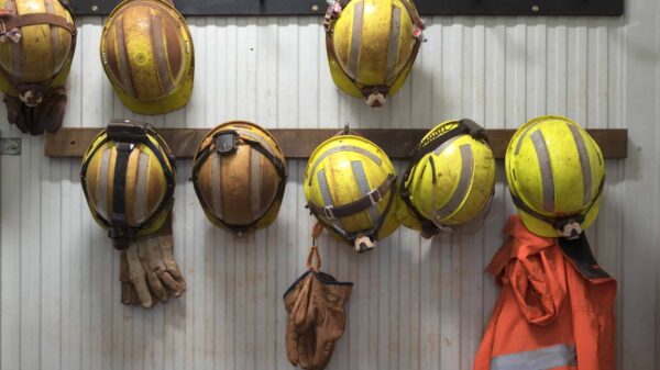 Safety helmets and gloves hang from a rack on a mining site.