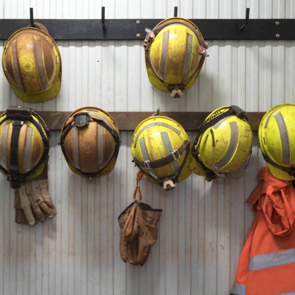 Safety helmets and gloves hang from a rack on a mining site.
