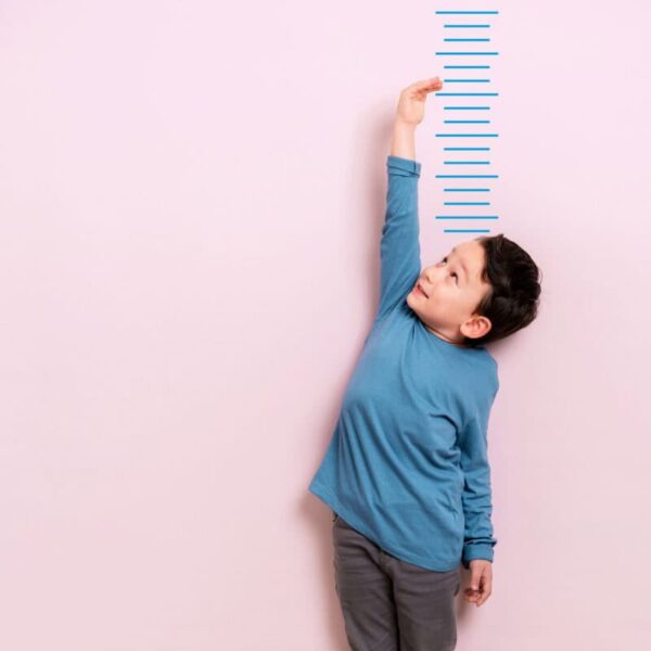 Child measures his height on wall. He is growing taller.